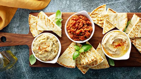 Houten plank met tapenade, hummus en pitabrood
